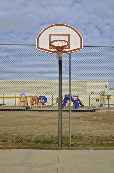 Obręcz do koszykówki przed szkolnym — Zdjęcie stockowe