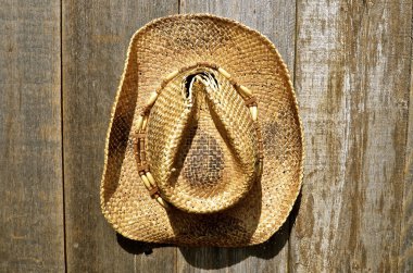 Old straw hats hangs on weathered wood wall clipart