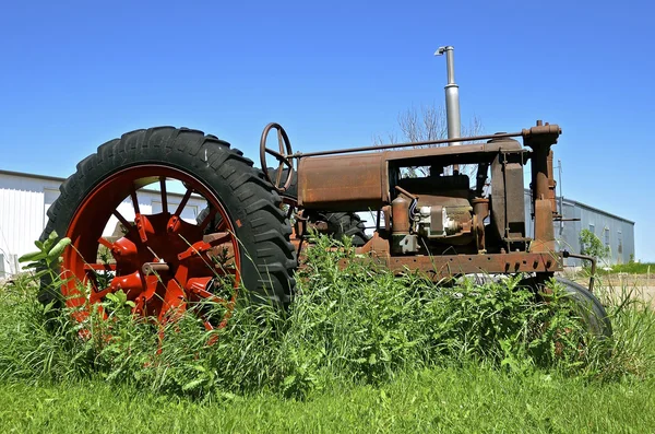 Viejo tractor en la maleza — Foto de Stock