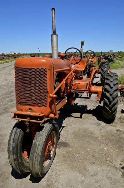 Starý oranžový traktor ve smetiště — Stock fotografie