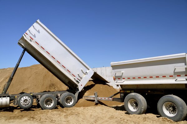 Trucks unload gravel at construction site