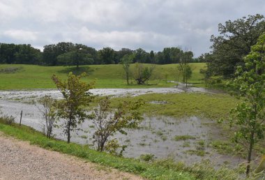 Şiddetli yağmur bulutları taşmış ovaları tepelik ve ağaçlık bir alanda bıraktı.. 