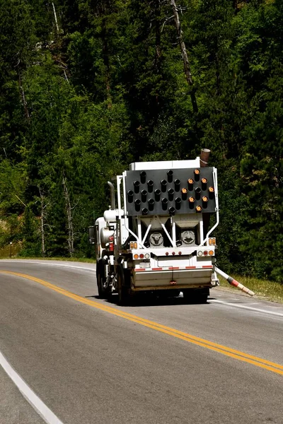 A service truck cleans the road of debris prior to painting white lines on a highway