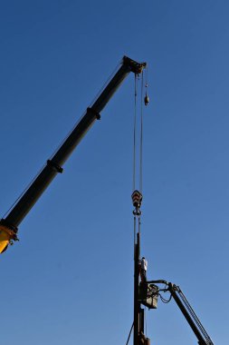Bir inşaat alanı vinci ve kablosu bir kaynakçının asansör ve kaynakların üzerinde durmasını sağlar.
