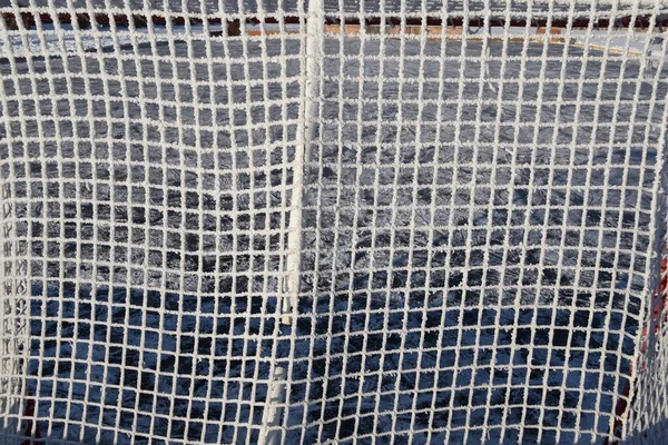 Hoar frost particles cover the netting of an outdoor hockey rick cage,