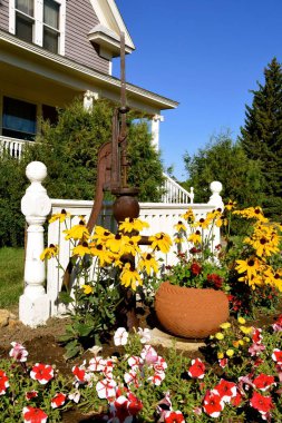 Paslı eski bir el pompası çiçeklerle çevrili bir bahçe dekorasyonu görevi görür..