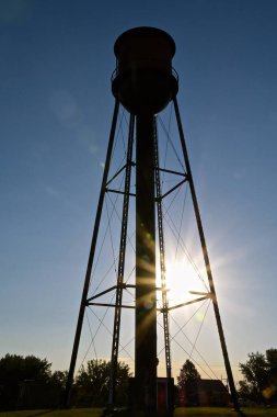 Sabahın erken saatlerinde gökyüzünde siluete dönüşen eski bir kasaba su kulesinde güneş ışığı parlıyor.