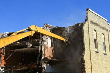 Kazı makinesinin kolu, yıkım sürecinde bir tuğla binanın içine doğru uzanıyor.. 