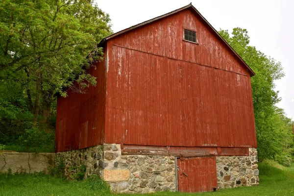 红色的旧谷仓有一个巨大的干草阁楼 安放在由大石头制成的地基上 — 图库照片