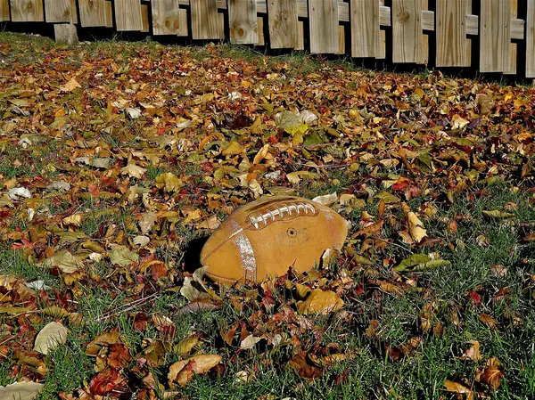 Futebol de couro velho nas folhas — Fotografia de Stock