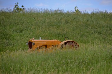 Yellow tractor hidden in grass clipart
