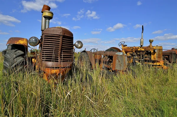 Oude trekker omgeven door gras en onkruid — Stockfoto