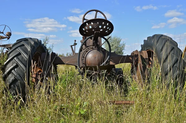 Vieux tracteur entouré d'herbe et de mauvaises herbes — Photo