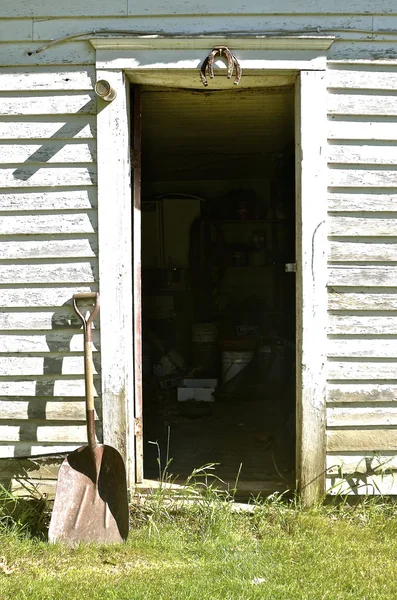 Old rusty shovel leans by door frame frame — Stock Photo, Image