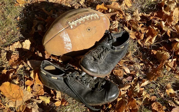 Futebol de couro velho e sapatos com picos — Fotografia de Stock