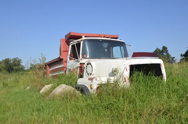 Oude vrachtwagen frame omgeven door gras en rotsen — Stockfoto