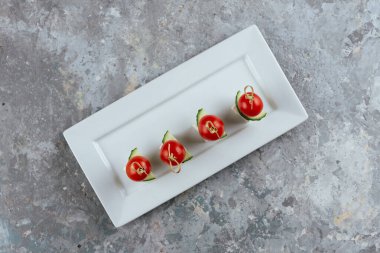 Gri arka planda beyaz tabakta domatesler.