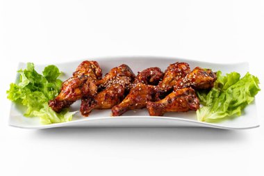 Sos ve salata yapraklı ızgara tavuk kanadı.