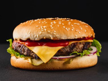 Siyah arka planda sığır etli ve peynirli hamburger. 