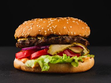 Siyah arka planda sığır etli ve peynirli hamburger. 