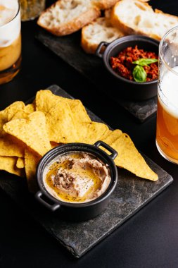 Siyah arka planda soslu bira cipsi ve kraker.