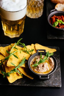 Siyah arka planda patates cipsi ve peynirli bira..