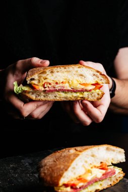 Siyah arka planda sandviçi olan adam.