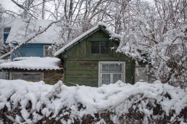 Kış ormanı manzarası ve karla kaplı eski ahşap evleri olan otantik bir köy.