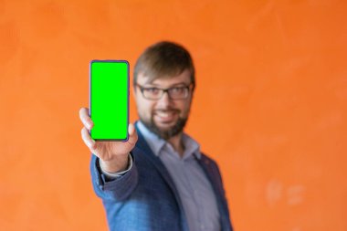 İnsan sağ kolu, video üretimi için yeşil ekranlı siyah cep telefonu tutuyor.