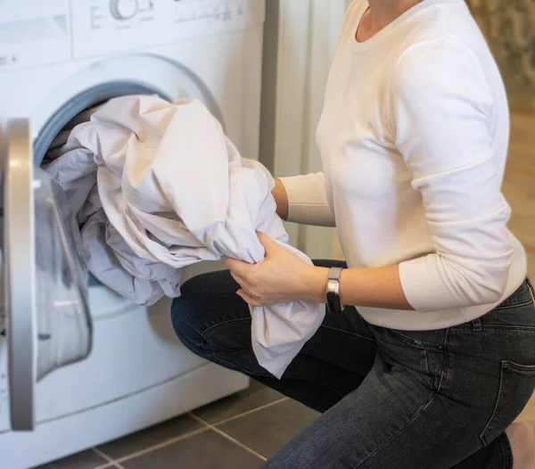 Foto de cerca de las manos femeninas sacando ropa blanca limpia de la lavadora — Foto de Stock