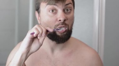 Yakışıklı sakallı adam dişlerini fırçalıyor.