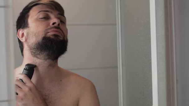 L'uomo raderà la barba con rasoio nero in bagno davanti allo specchio — Video Stock