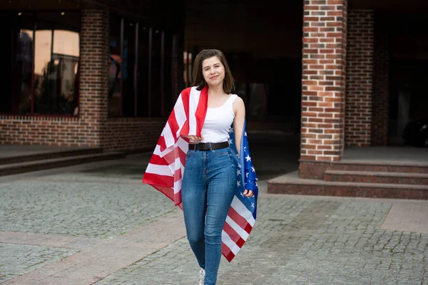 Νεαρή γυναίκα προστατευμένη από την αμερικανική σημαία χαμογελώντας και γιορτάζοντας την 4η Ιουλίου ημέρα ανεξαρτησίας — Φωτογραφία Αρχείου