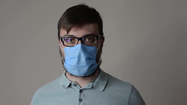 Sakallı ve gözlüklü yakışıklı adam koruyucu maskeyi çıkarıyor. — Stok video