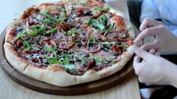 Close-up do lado de uma mulher é dilacerado por pedaços de pizza italiana com pepperoni, arugula — Vídeo de Stock