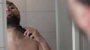 Adamın sakalını traş edip aynanın yansımasına baktığı yakın plan.