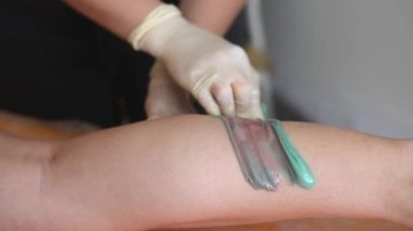 Güzellik salonunda kadın bacağına ağda yapan bir güzellik uzmanı. Bacaklar titriyor.