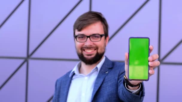 Зеленый экран телефона изолирован на фиолетовом фоне в руках мужчины — стоковое видео