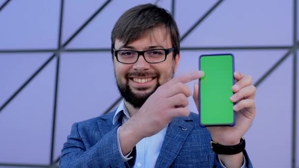 Grön skärm telefon isolerad på lila bakgrund i händerna på en man — Stockvideo
