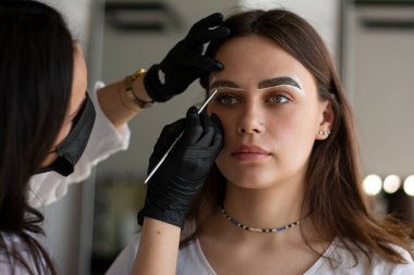 Genç bir esmerin kaşlarını boyama işlemi bir kaş ustası tarafından boyalı boya ile