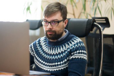 Bilgisayarda çalışan, masa başında oturmuş kod yazan bir adam.