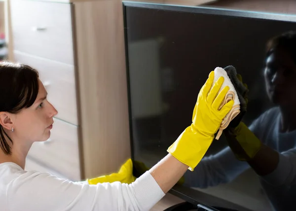 Reinigungsservice professionelle Hausreinigung Staubwischen mit einem Lappen und in Handschuhen TV-Bildschirm — Stockfoto