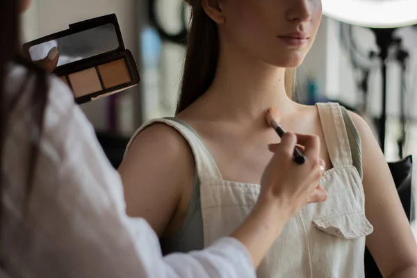 Artista de maquiagem profissional aplica sombras ao corpo dos modelos com uma escova de maquiagem — Fotografia de Stock