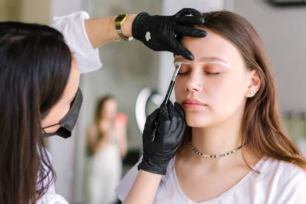 The brow artist prepares the model for the application of eyebrow dye