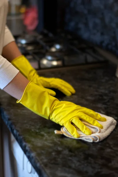 Hausfrau putzt Haus mit gelben Handschuhen wischt Staub vom Küchentisch auf den Teller — Stockfoto
