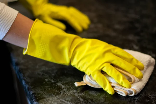 Hausfrau putzt Haus mit gelben Handschuhen wischt Staub vom Küchentisch auf den Teller — Stockfoto