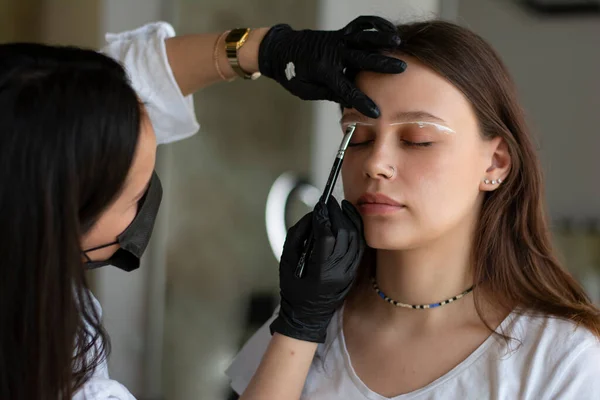 Mulher jovem submetida a procedimento de correção de sobrancelha no salão de beleza, close-up — Fotografia de Stock