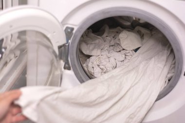 Çamaşır makinesinden beyaz çarşaf çıkarmanın yakın plan çekimi.