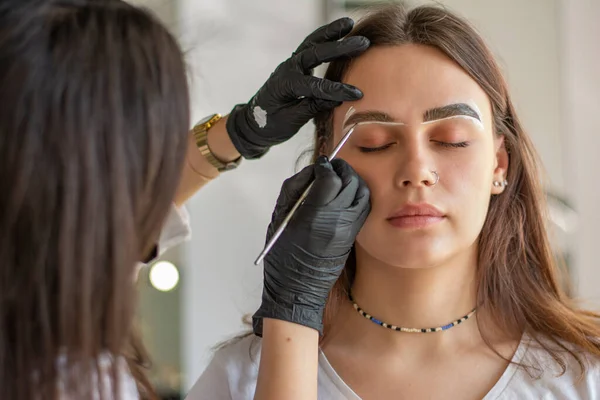 Mulher jovem submetida a procedimento de correção de sobrancelha no salão de beleza, close-up — Fotografia de Stock