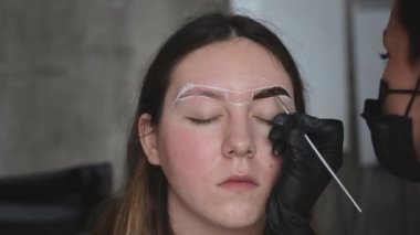 Güzellik salonunun ön cephesinden ince fırça darbesi ile kaşlara boya sürüyorum.